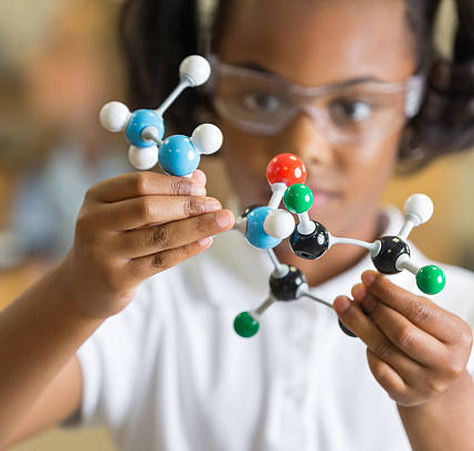 Elementary science student using plastic atom model educational toy
